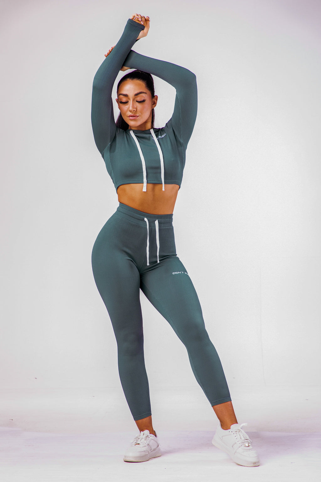 A woman wearing a navy blue coloured gym clothing with a matching long sleeve hoodie cropped top 
