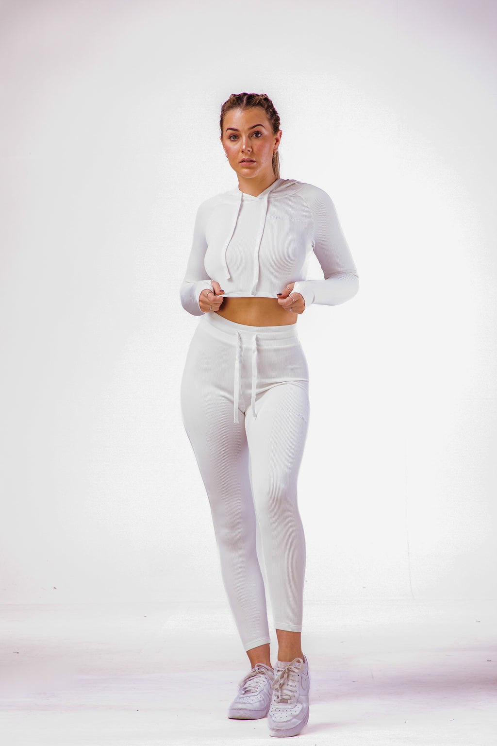A woman wearing a white coloured gym clothing with a matching long sleeve hoodie cropped top 
