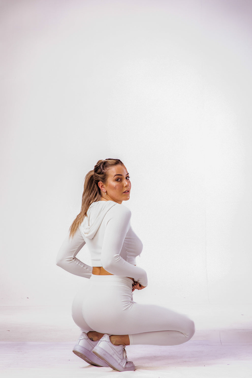 A woman wearing a white coloured gym clothing with a matching long sleeve hoodie cropped top 