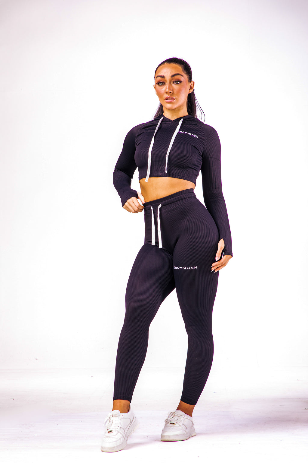 A woman wearing a black coloured cropped top with hoodie with a pair of matching leggings