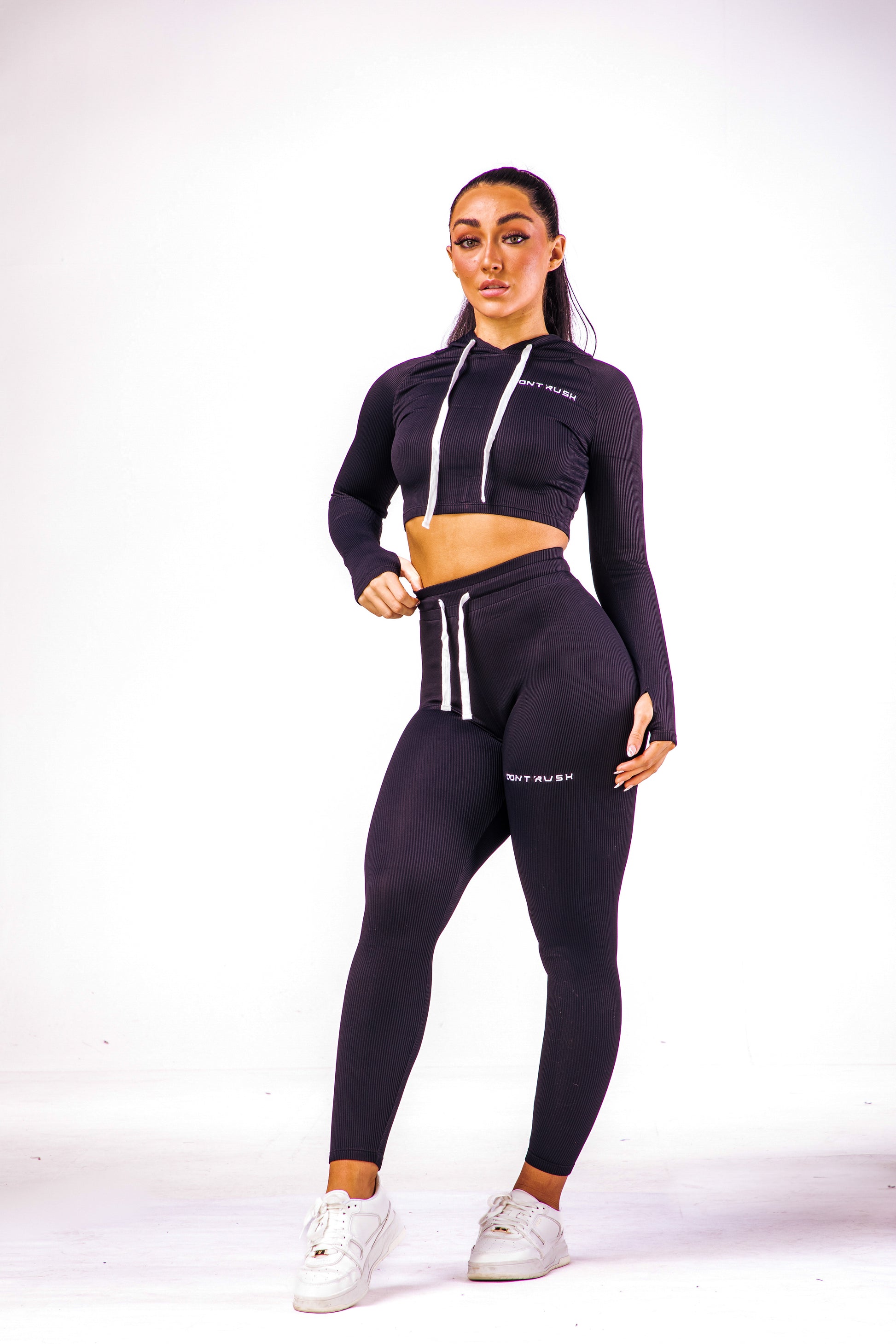 A woman wearing a black coloured cropped top with hoodie with a pair of matching leggings
